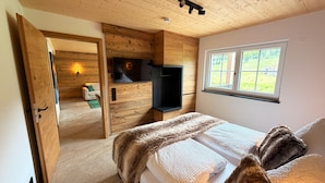 Une chambre à coucher avec un lit, une télévision, une fenêtre et un plafond en bois.