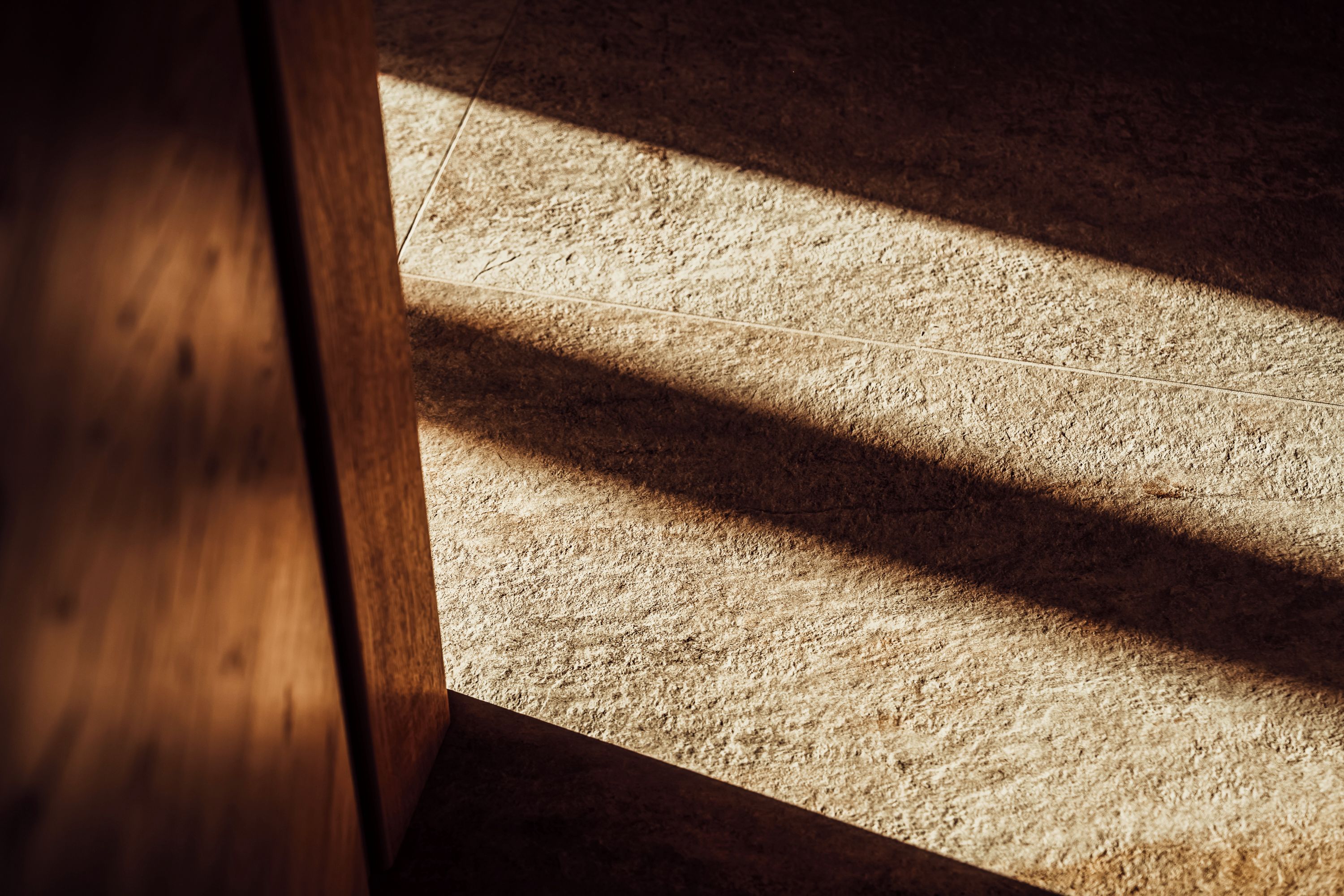 A wooden floor with a shadow cast by a wooden structure.