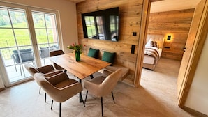 Un intérieur moderne avec une table à manger en bois, des chaises, un téléviseur à écran plat et un canapé dans une pièce accueillante.