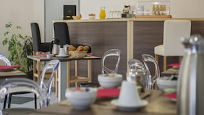A modern cafe with clear glass chairs, a counter with breakfast items, and pendant lighting. - Stay in Les Eyzies With Pool (Les Eyzies)