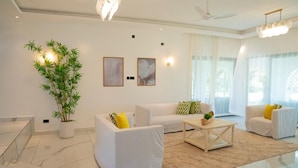 A modern living room with white sofas, a coffee table, a large potted plant, and artwork on the walls. - Creek Side, Ocean View 5-bedroom villa, with a private Coastal feel in Mombasa (Mombasa)