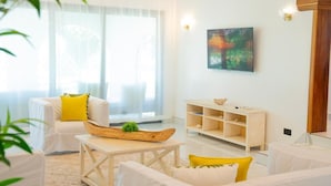 A modern living room with white furniture, a wooden coffee table, and a large window with sheer curtains. - Creek Side, Ocean View 5-bedroom villa, with a private Coastal feel in Mombasa (Mombasa)