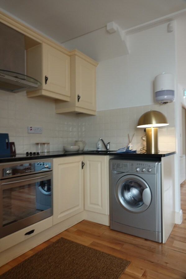 A kitchen with a washing machine, oven, and cabinets. - The Yellow Door situated in the heart of Kinvara, on the Wild Atlantic Way. (Kinvarra)