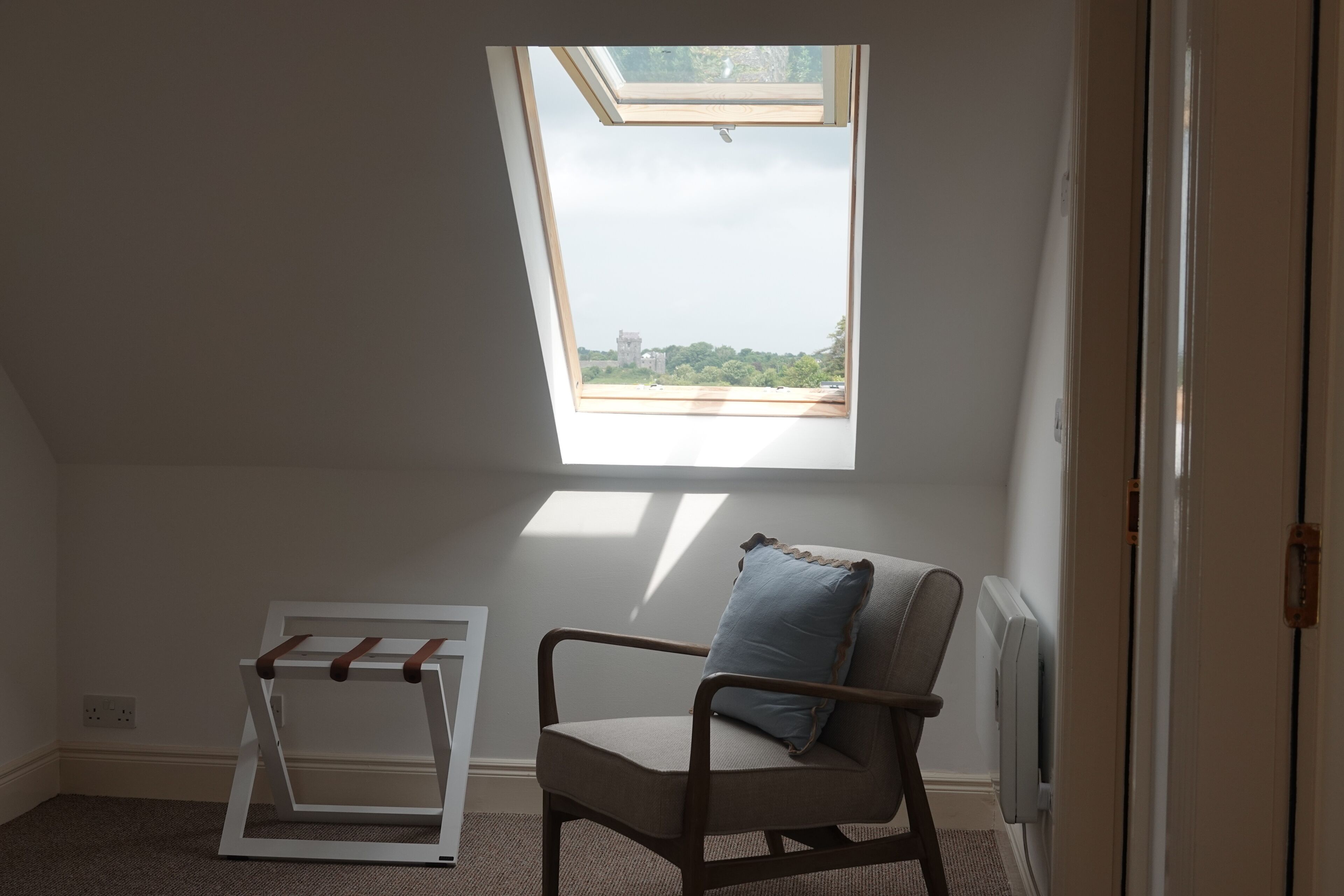 A room with a skylight, a chair with a cushion, and a white radiator.