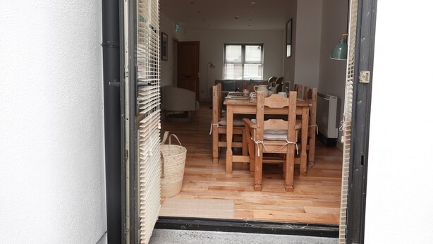 A dining area with a wooden table and chairs, a wicker basket, and a door leading to another room.