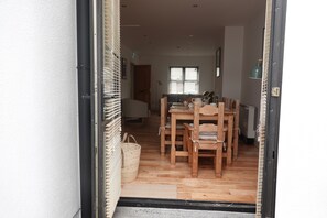 Un comedor con una mesa y sillas de madera, una cesta de mimbre y una puerta que da a otra habitación.