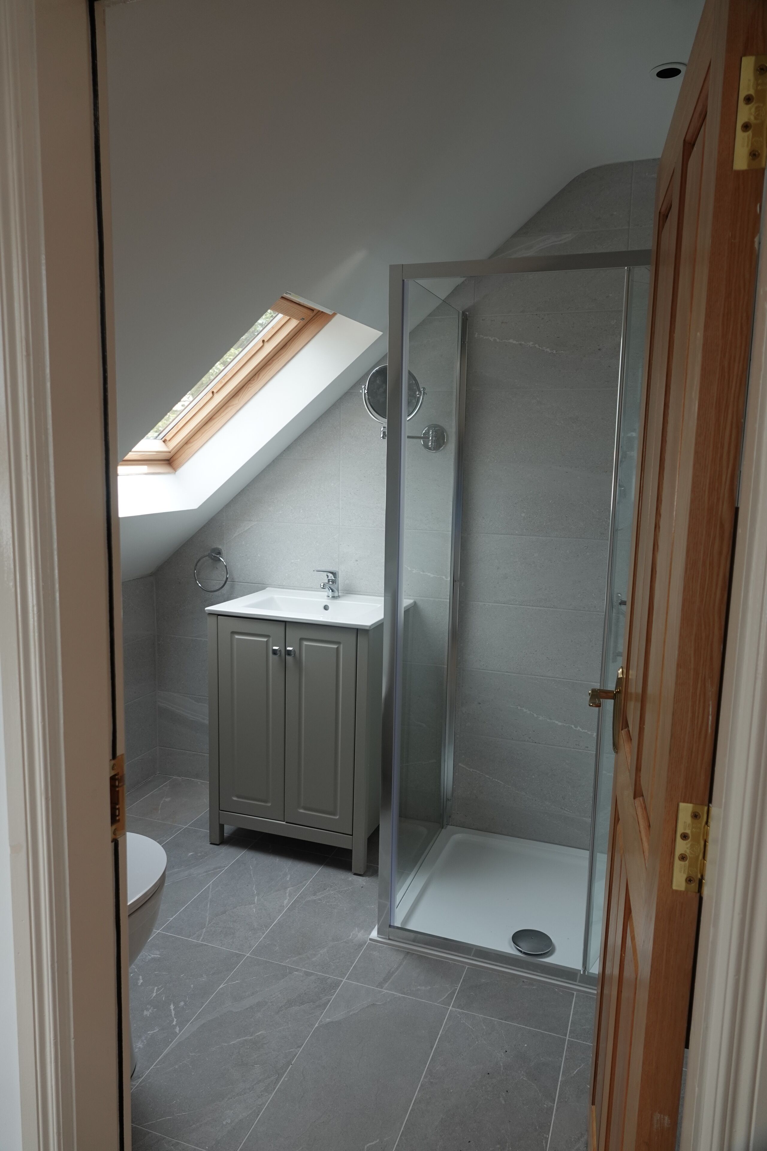 Un bagno con finestra sul tetto, doccia e toilette.