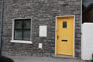 Un edificio de piedra con una puerta amarilla y una ventana con persianas.