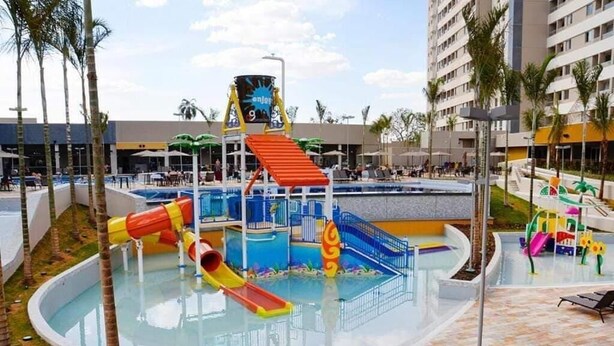 Ein Wasserpark mit Rutschen und Pool, umgeben von Palmen und Hotelgebäuden.