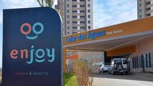 Schild für 'enjoy Hotels & Resorts' und 'Solar das Águas Park Resort' mit einem Parkplatz und Gebäuden im Hintergrund.