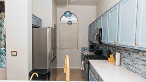 A kitchen with a refrigerator, stove, and microwave. There is a window with blinds, a sink with a gold faucet, and cabinets with gold handles. - NEW Canoa Ranch Retreat (Green Valley)