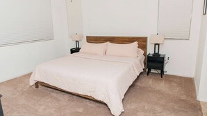 A bedroom with a bed, two bedside tables, a wooden headboard, and a carpeted floor. - NEW Canoa Ranch Retreat (Green Valley)