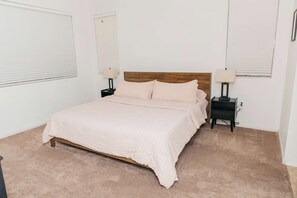 Ein Schlafzimmer mit einem Bett, zwei Nachttischen, einem Holz-Kopfteil und einem Teppichboden.