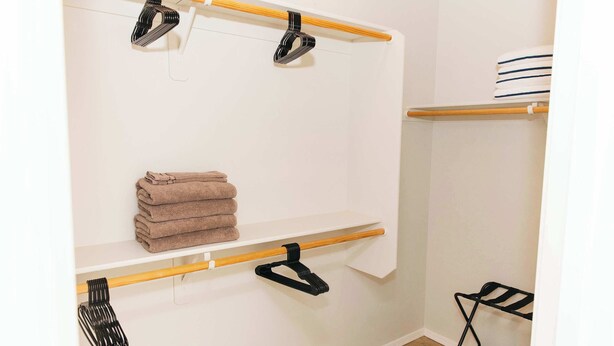 A bathroom with a towel rack, a shelf with folded towels, and a black chair. - NEW Canoa Ranch Retreat (Green Valley)