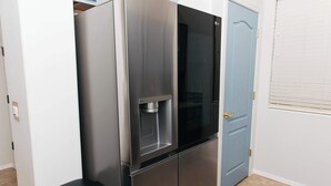 A stainless steel refrigerator with a water dispenser, a black countertop, and a blue door in a room with white walls and a tiled floor. - NEW Canoa Ranch Retreat (Green Valley)