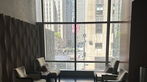 Ein modernes Interieur mit einem großen Fenster, einer geschwungenen Wandgestaltung und einer Sitzecke mit zwei Sesseln.