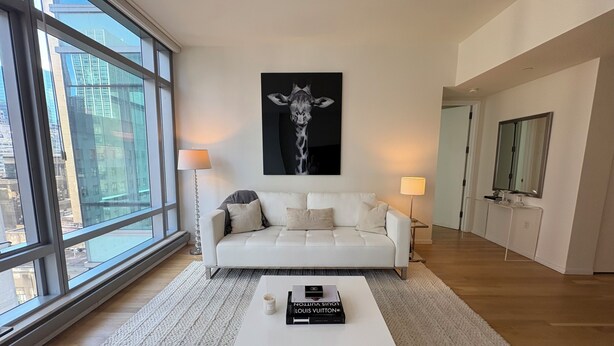 Ein modernes Wohnzimmer mit einem weißen Sofa, einem Couchtisch und einem großen Fenster mit Blick auf die Stadt.
