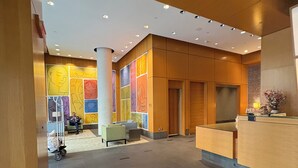 Eine Hotelhalle mit Empfangstresen, Sitzgelegenheiten und einer Wand mit farbenfroher Kunst.