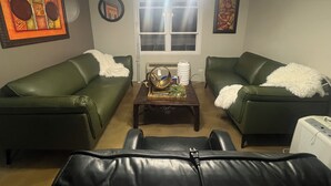 Ein Wohnzimmer mit zwei grünen Sofas, einem Couchtisch mit Dekoration, einer Deckenleuchte und einem Fenster.