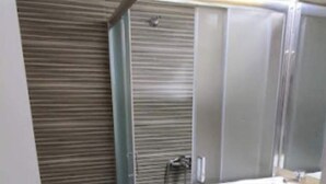 Casa de banho com sanita, cabine de duche, lavatório e máquina de lavar roupa.