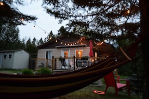 Una casa con terraza, luces colgantes y una hamaca.