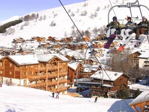 A ski resort with wooden buildings, a ski lift, and snow-covered terrain. - Appartment in Vaujany (Les Deux Alpes)