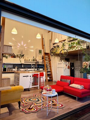 Eine moderne Küche mit Essbereich, einem roten Sofa und einem gelben Sessel.