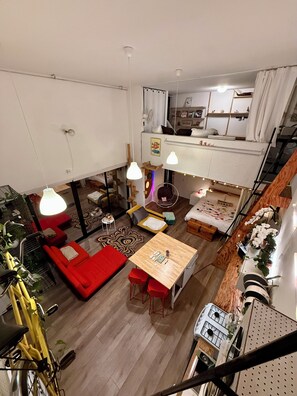 Eine moderne Wohnung mit Schlafgalerie, Essbereich und Wohnraum mit rotem Sofa und gelbem Fahrrad.