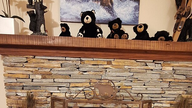 A fireplace with a stone surround, decorative bear figurines, and a bear-themed painting on the wall. - B cabin 2-bedroom with AC in charming Blowing Rock (Blowing Rock)
