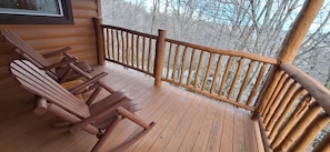 Eine Holzterrasse mit Adirondack-Stühlen und einem Hollergeländer.