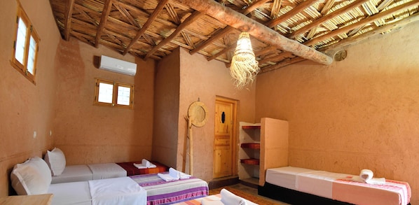 A hotel room with two beds, a wooden ceiling, and a small window.