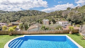 Uma piscina cercada por uma vedação de madeira, com casas e árvores ao fundo.