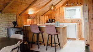 A wooden cabin interior with a kitchen, bar area, and dining space. - Simple living right next to the sea (Græsted)