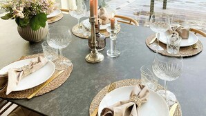 A dining table set with placemats, plates, cutlery, and candles, with a view of greenery outside. - Modern holiday home by Holbæk Fjord (Holbæk)