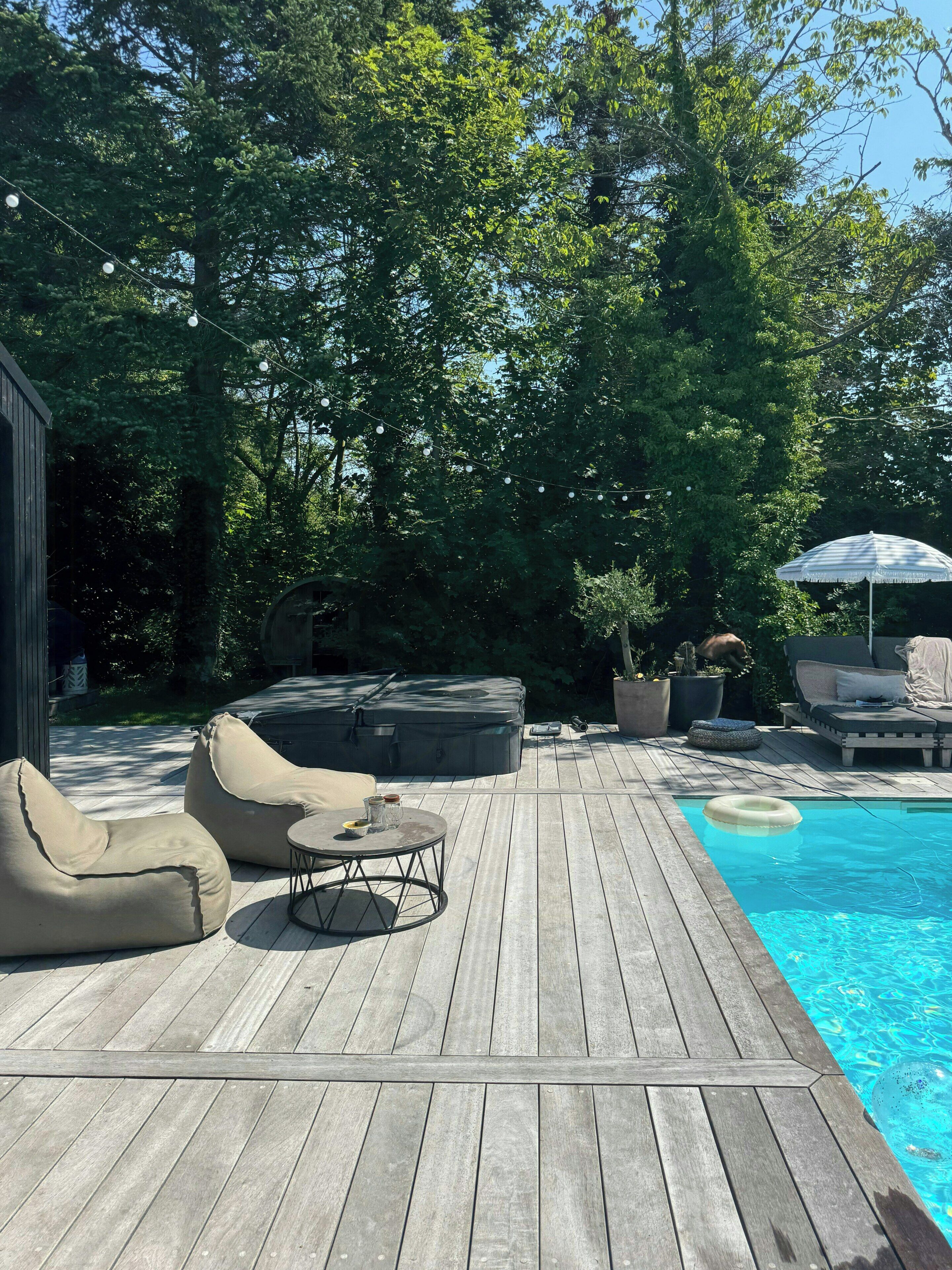 Une terrasse en bois avec une piscine, un espace salon extérieur et un jacuzzi.