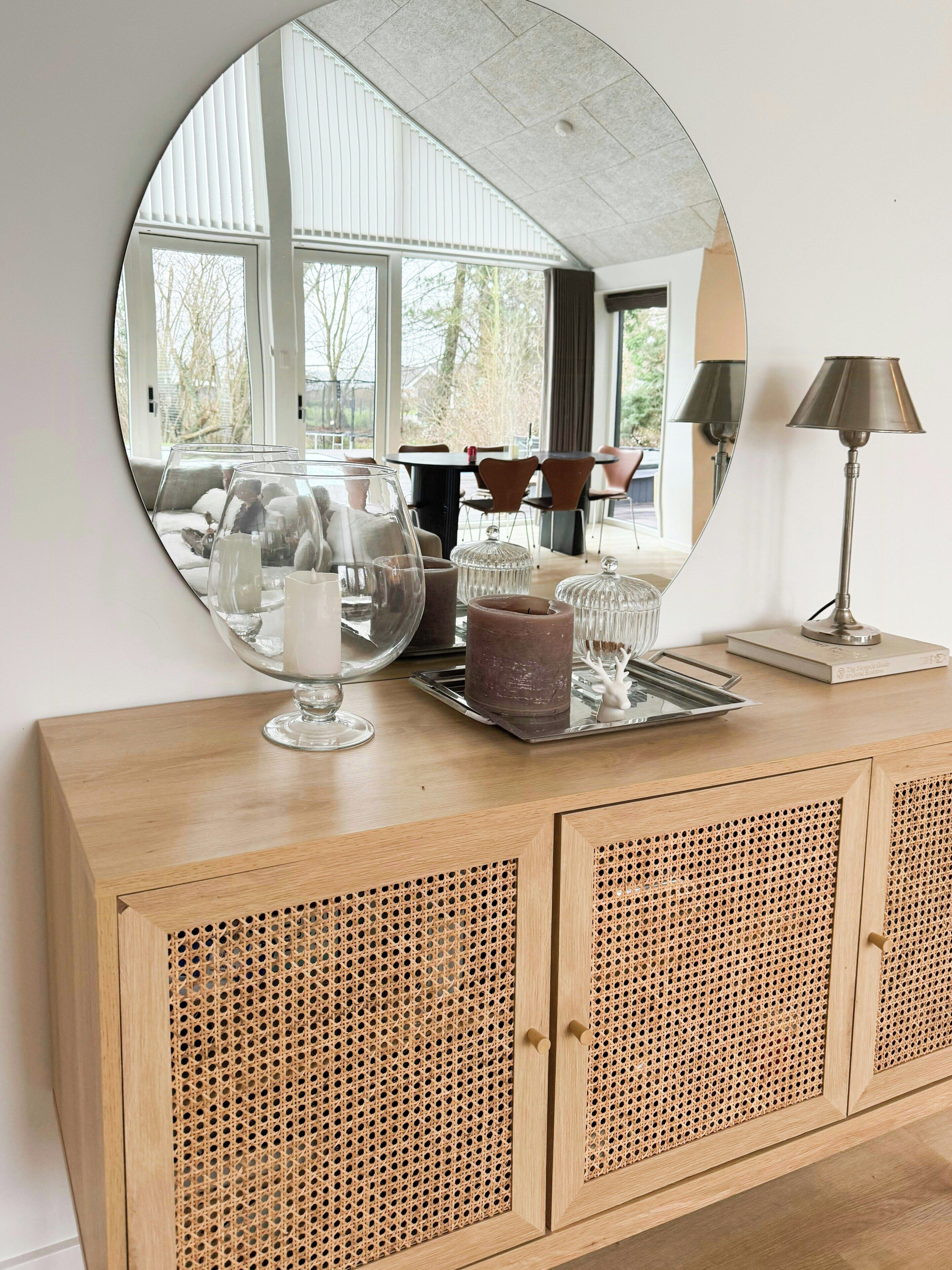 Un mueble de madera con un espejo grande, una lámpara y objetos decorativos.