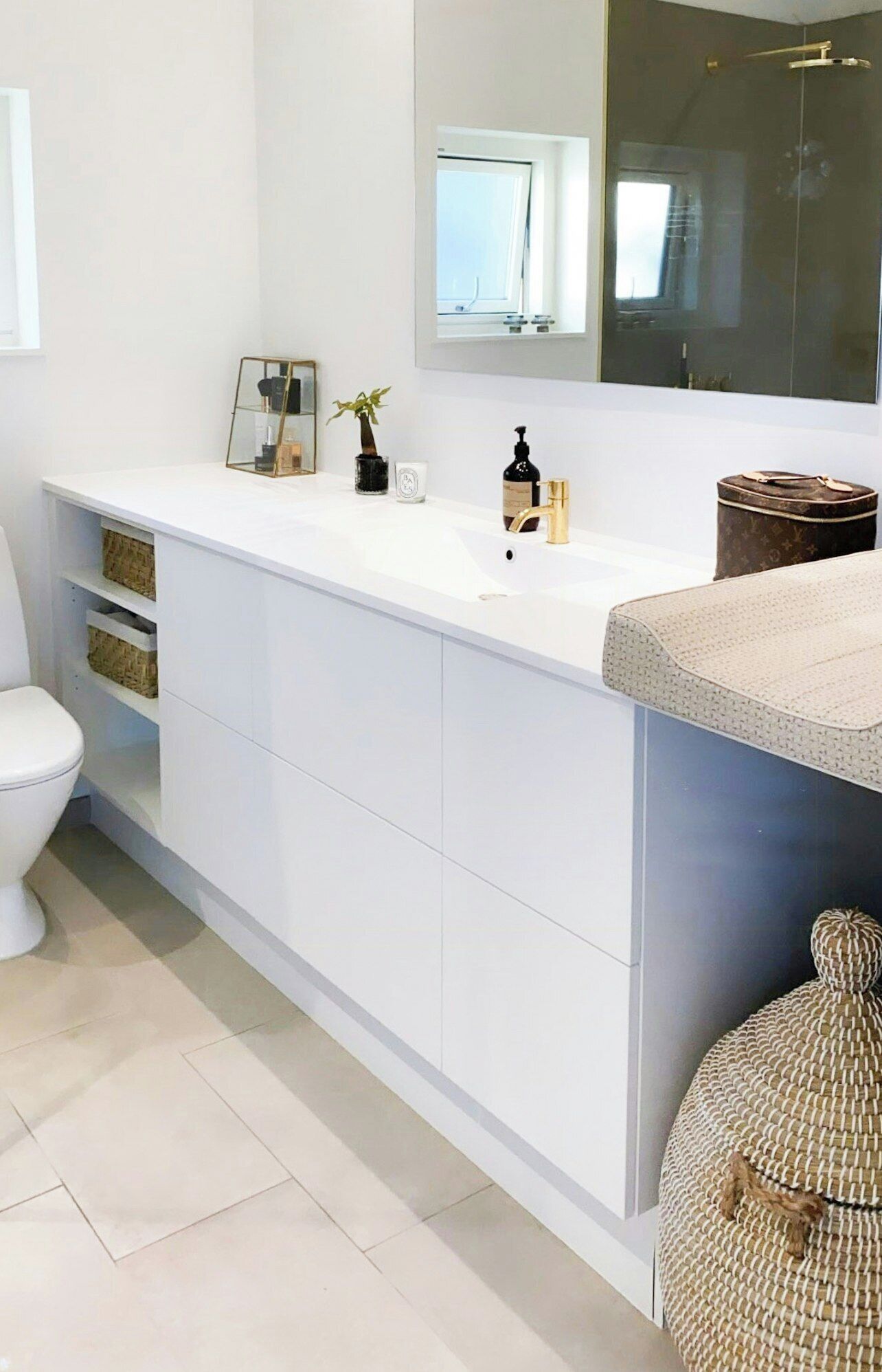 Een moderne badkamer met een wit wastafelmeubel, een toilet en een grote spiegel.