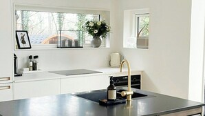 A modern kitchen with a large island, white cabinetry, and a view of the outdoors. - Modern holiday home by Holbæk Fjord (Holbæk)