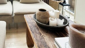 A modern living room with a sofa, a wooden table with candles, and a view of the outdoors. - Modern holiday home by Holbæk Fjord (Holbæk)