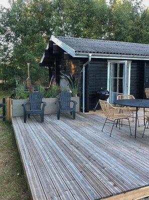 A wooden deck with outdoor furniture, a grill, and a garden area.
