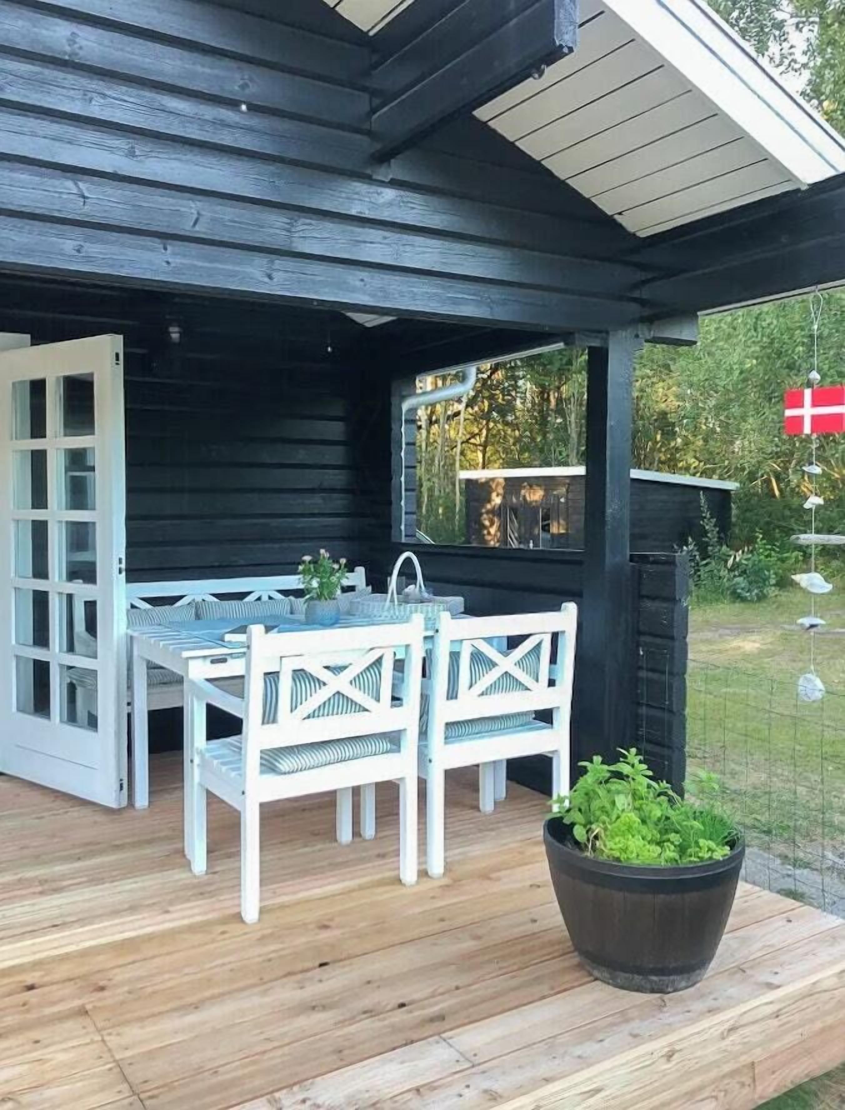A wooden deck with a table and chairs, a potted plant, and a flag.