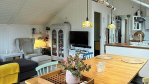Ein gemütliches Wohnzimmer mit Esstisch aus Holz, einem Fernseher und einem Bücherregal.