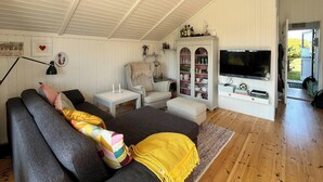 Ein gemütliches Wohnzimmer mit einer Couch, einem Fernseher, einer Vitrine und Holzboden.