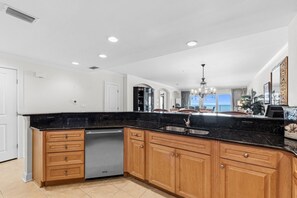 A spacious kitchen with a black countertop, wooden cabinets, and a built-in dishwasher.