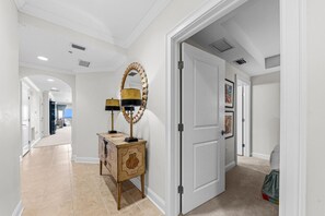 A hallway with a wooden cabinet, a mirror, and a door leading to another room.