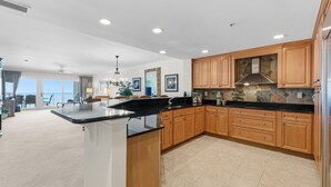 A spacious kitchen with wooden cabinets, a black countertop, and a view to the outside. - The Shoreline Suite Oceanfront (Jacksonville Beach)