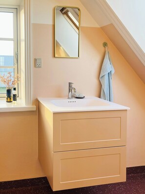 A bathroom with a white sink, a mirror, and a towel hanging on the wall. - Villa with fjord view by Frederik VII's Canal (Løgstør)