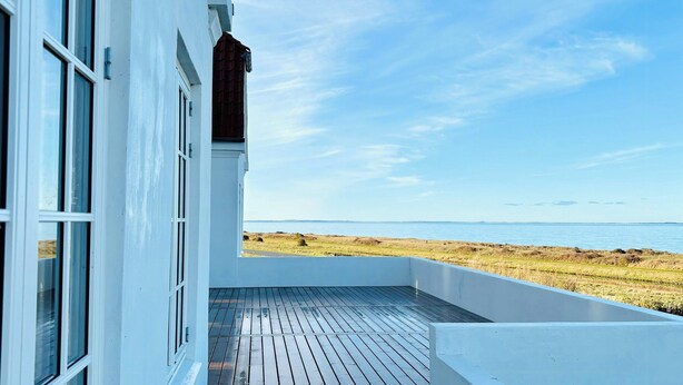 Un edificio con terraza de madera y vista a la playa.