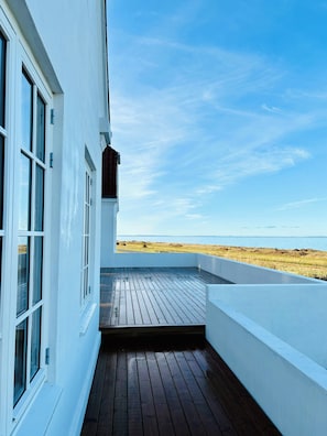 Un bâtiment doté d’une terrasse en bois et offrant une vue sur la plage.