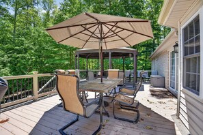 A covered outdoor patio with a table and chairs, surrounded by a wooden deck and a white railing. - Forest Cove Lake Anna | Hot Tub, Games & Boat Slip (Mineral)